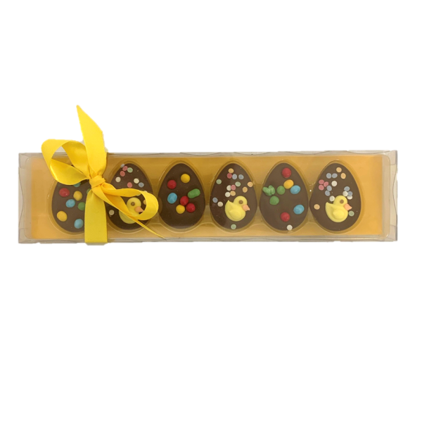 small half egg chocolates with easter spring decoration in a yellow box with yellow ribbon
